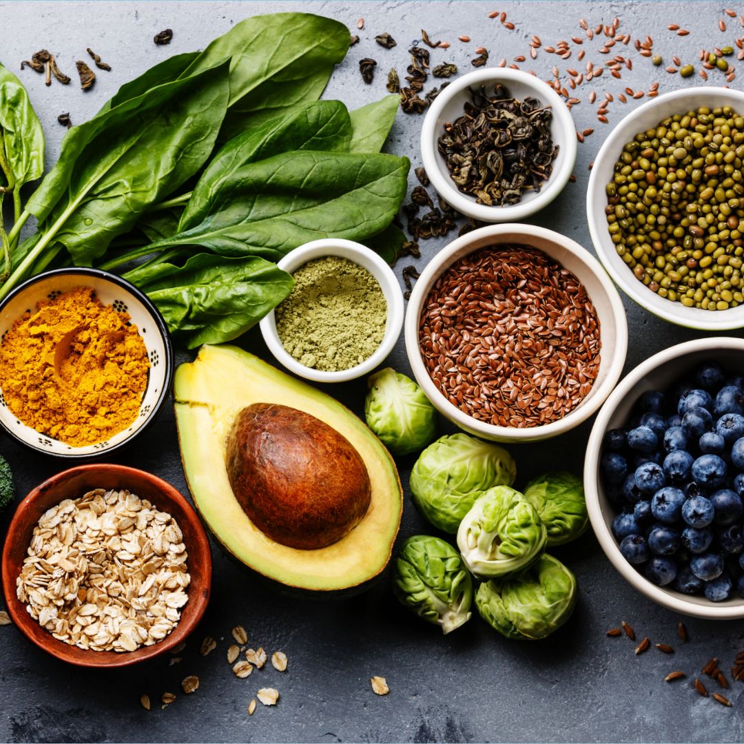 Flat lay showing PCOS-friendly food swaps: colourful vegetables, lentils, nuts, and berries replacing white bread and biscuits.