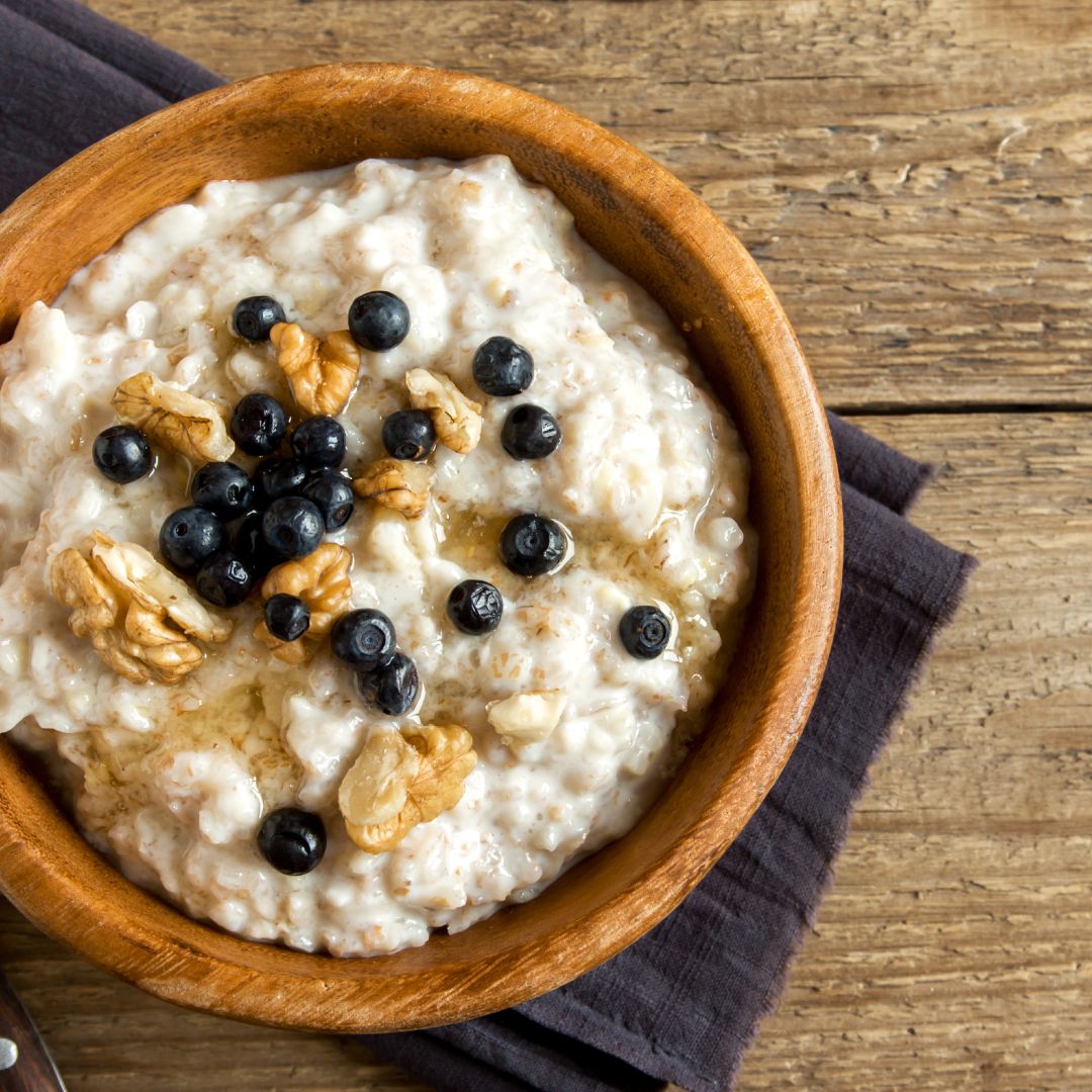 Bowl of porridge topped with nuts, seeds and berries for a balanced winter PCOS friendly breakfast.